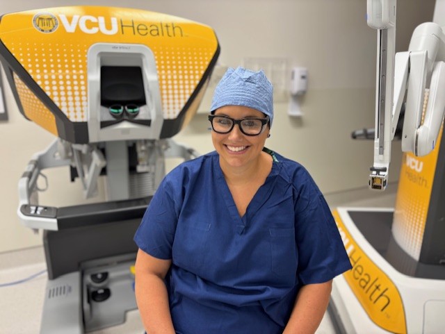 After recently undergoing gallbladder surgery, a hospital nurse sits next to the robotic arm that helped make the procedure less painful and shortened her recovery time.