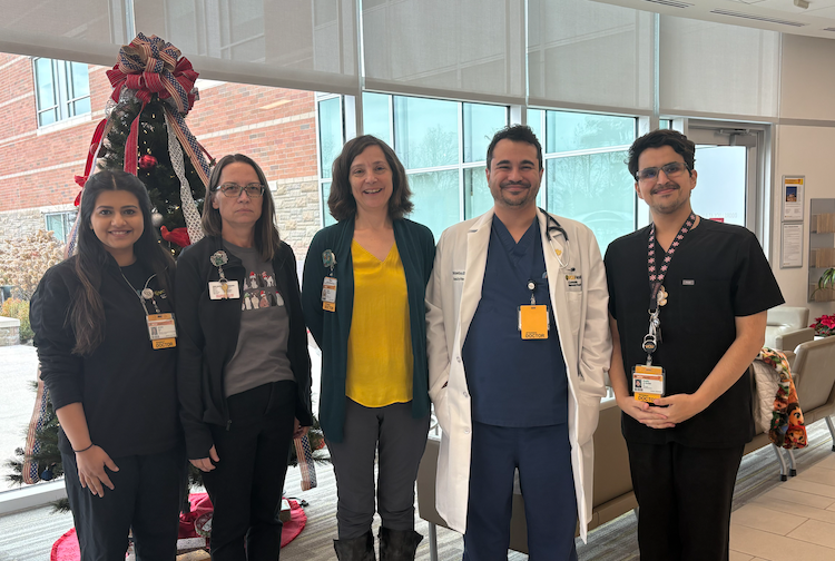 Medical residents and CMH team members training them are standing in front of a Christmas tree at the hospital.