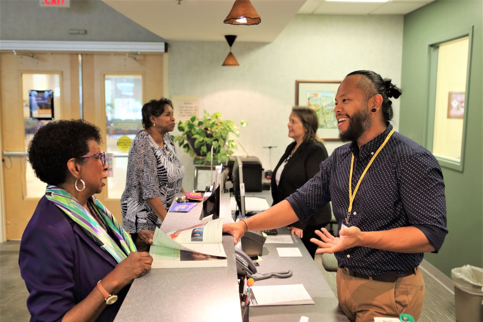 A couple of front-desk team members helping patients in the library.