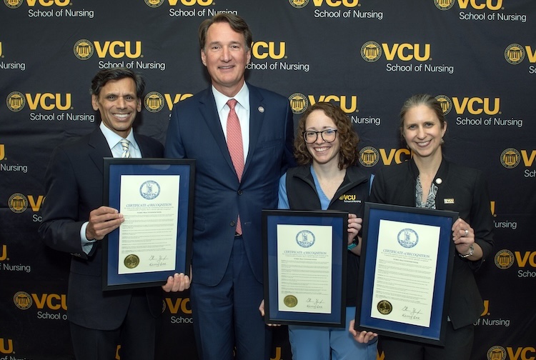 Four people stand together with proclamations