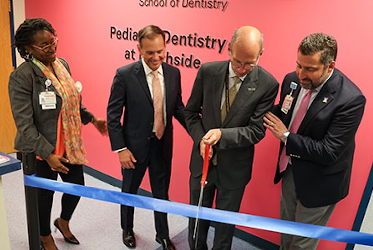 four people standing together to cut the ribbon on the new facility