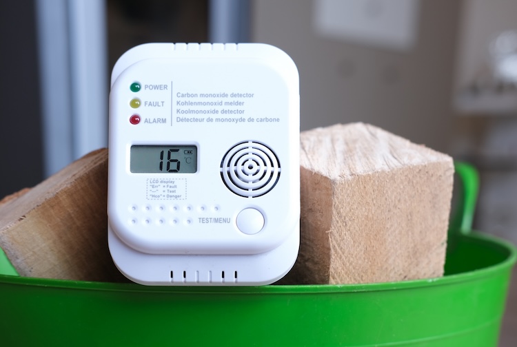 Carbon monoxide alarm in a basket of firewood in an apartment in front of a fireplace