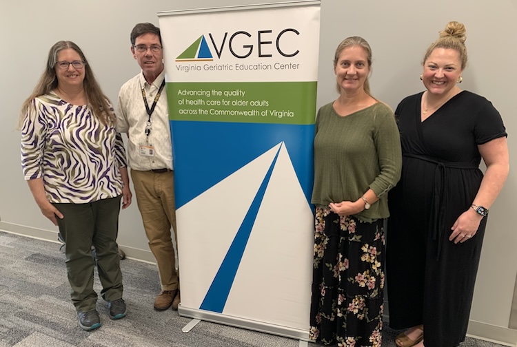 Four people standing together near a sign