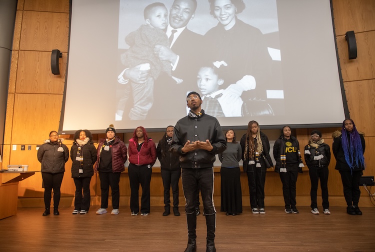 Choir singings in front of images of Dr. Martin Luther King Jr. and his family.