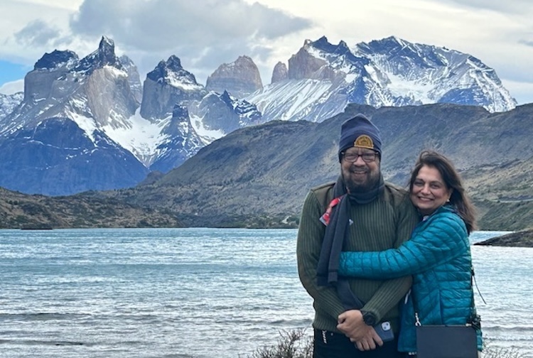 Bryjinder and Ranju Kohli stand by a lake in front of mountains