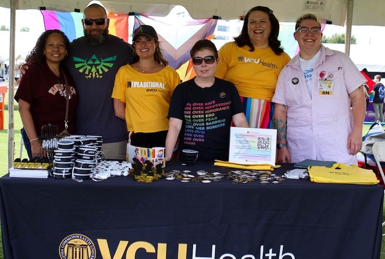 Group standing behind a table handing out VCU Health swag at a festival