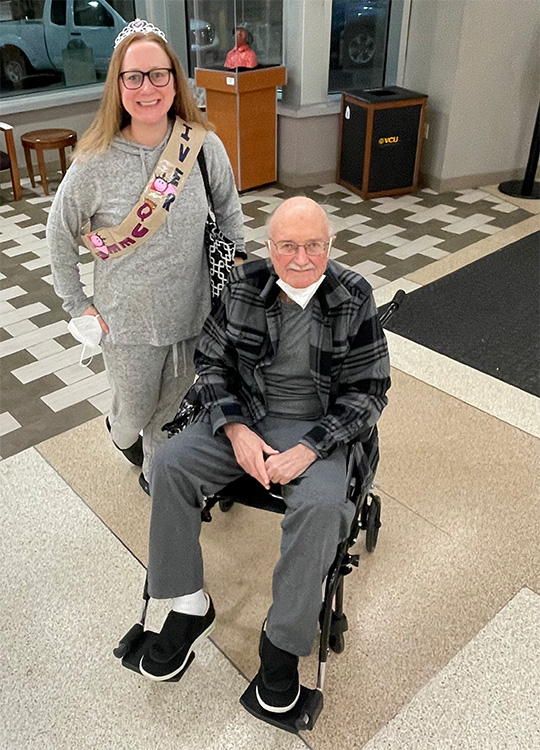 Man in wheelchair and woman standing, both smiling