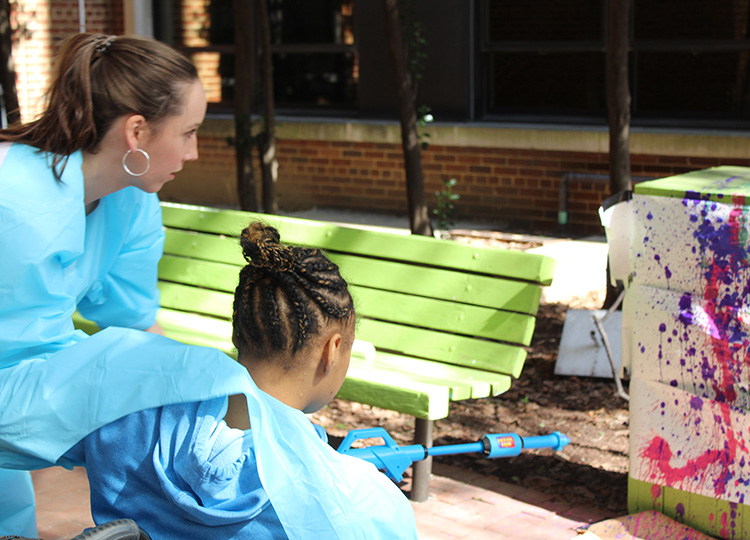 Provider and pediatric patient make a painting.