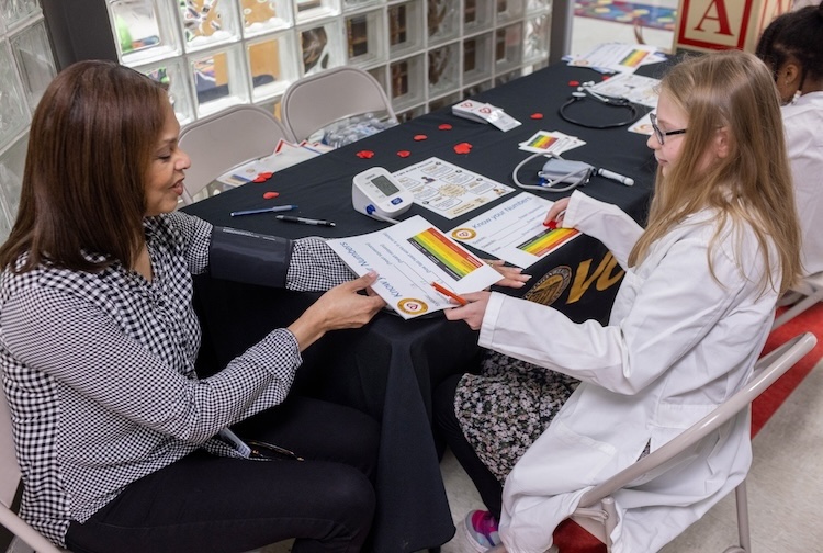 Young elementary school student shares blood pressure information with teacher