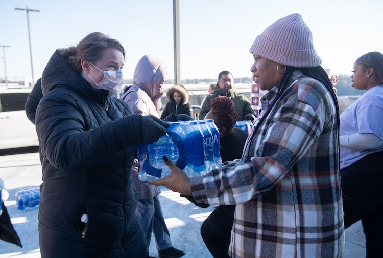 Hospital staff pick up bottled water in a parking lot