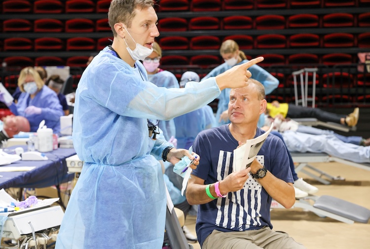 Man sits and waits for dental care while talking to dentist