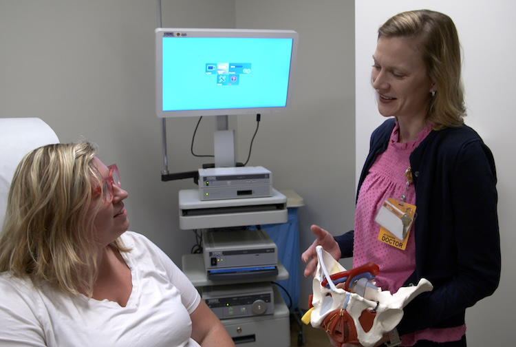 Dr. Burkett speaks with a patient while holding a replica of a woman’s pelvis.