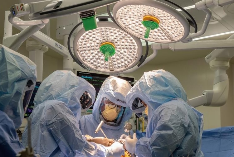 Surgeons in scrubs around an operating table