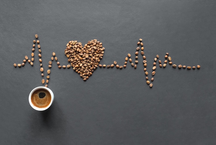 A cardiogram of coffee beans and a cup of coffee on a black background.