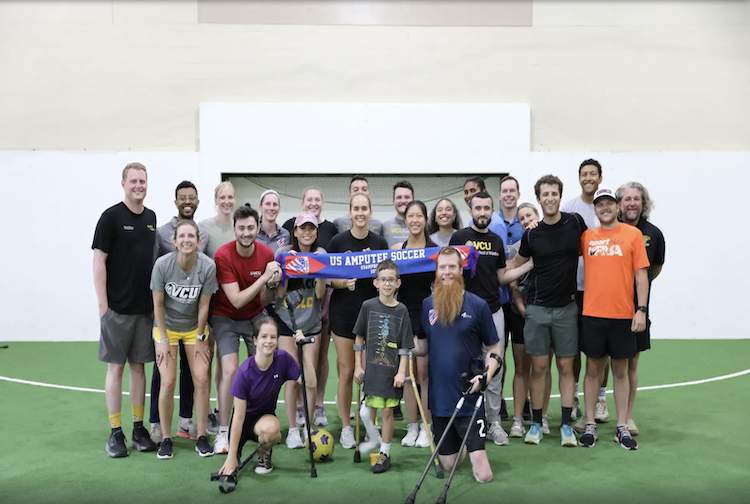 VCU's student adaptive sport group poses together holding US Amputee soccer banner.