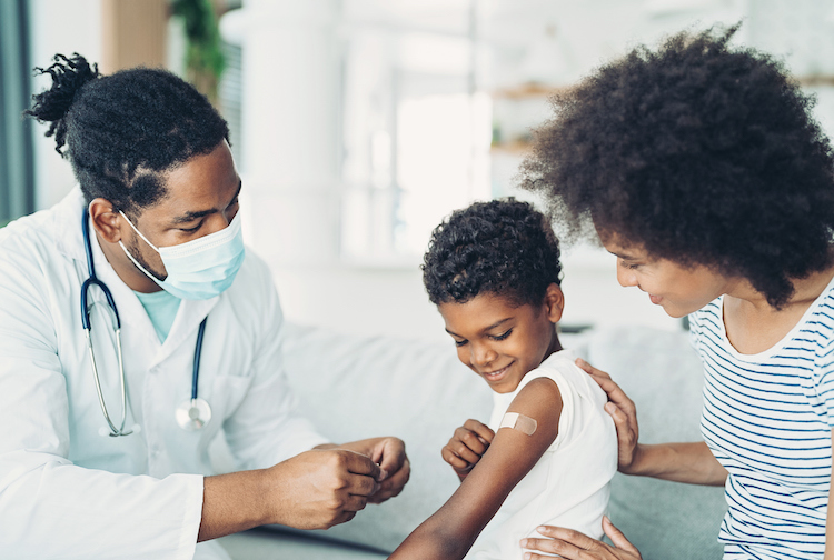 Little boy proudly looking at a bandaid, covering up his vaccine shot.