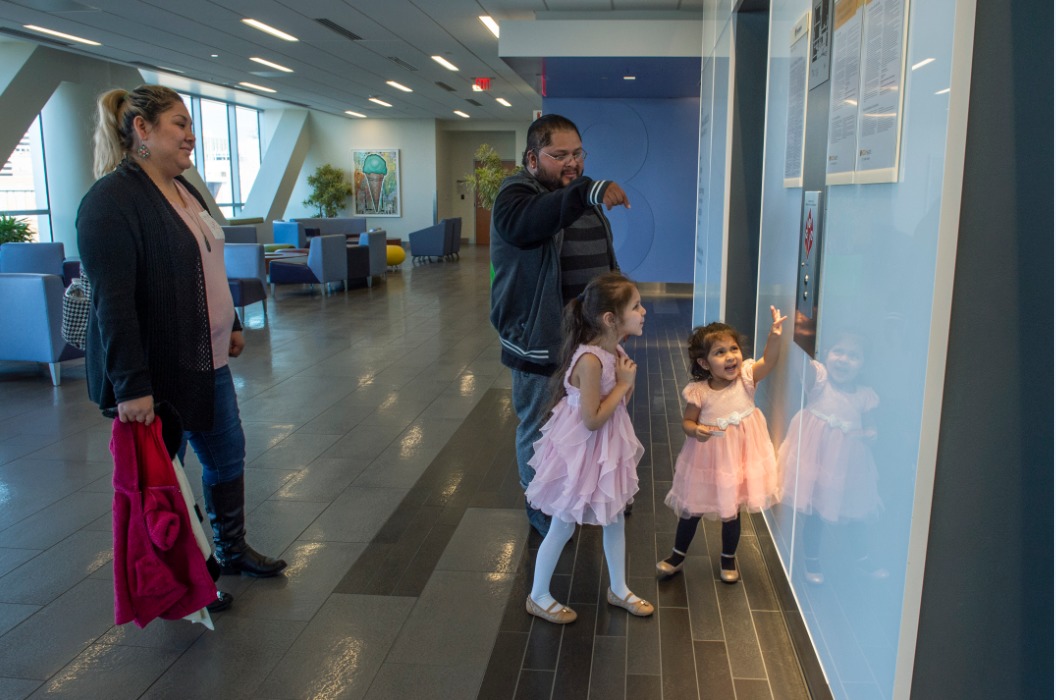 Roxana Sanchez and Jorge Cubas assist their daughters, from left, Astrid Cubas-Sanchez and Roxanne Cubas-Sanchez as they call for an elevator at the Children's Pavilion following a recent appointment. (Photo by Kevin Morley, University Relations)