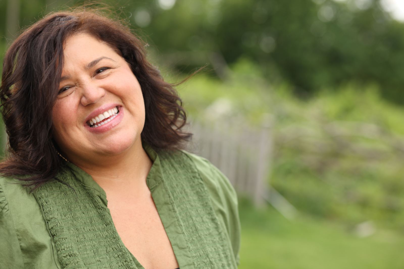 Hispanic woman wearing a green shirt and smiling.